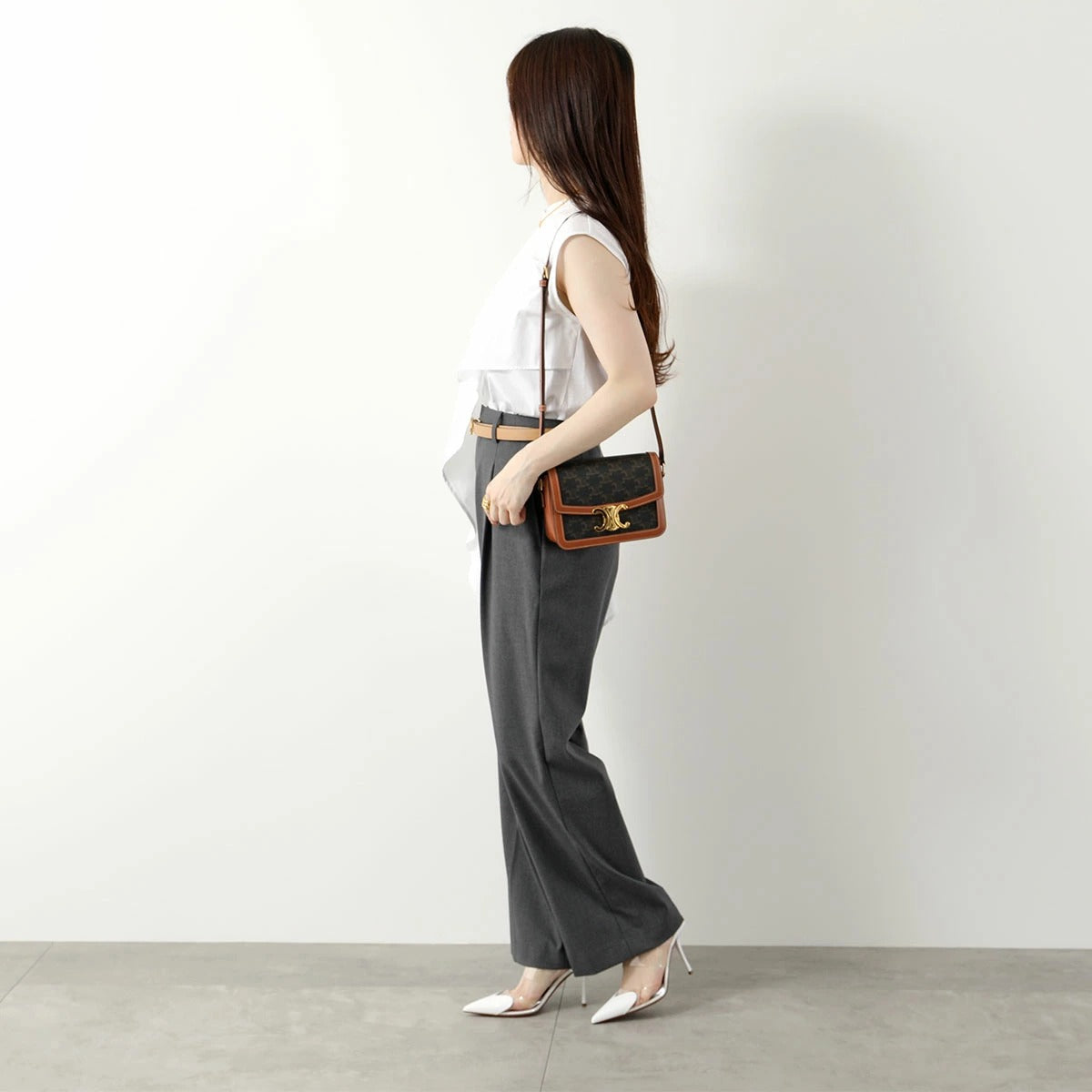 Woman holding a Celine Teen Triomphe Bag In Triomphe Canvas & Calfskin 188882BZ4.04LU against a plain background
