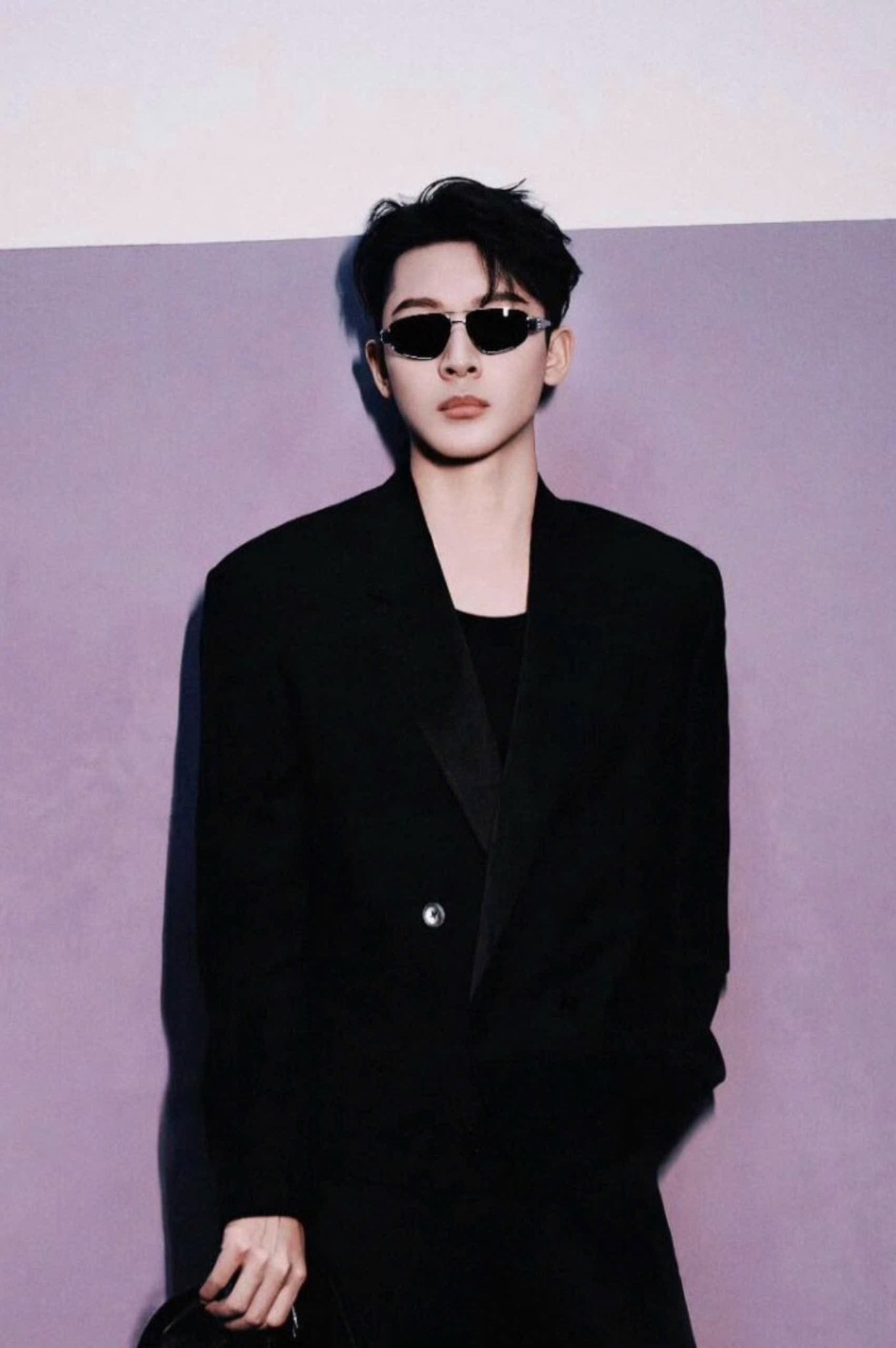 Person wearing a black suit and Celine Triomphe Metal 03 Sunglasses in Metal – CL40281U 16A against a light purple background