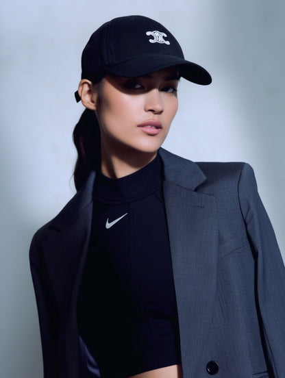 Person wearing a Celine Vivienne Cap in Cotton Twill Black & White AA0GV2U74.37BW with a triomphe logo, black turtleneck, and gray coat against a light gray background