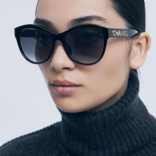 Person wearing a pair of Chanel CH5458 C622T8 Round Sunglasses with a plain background