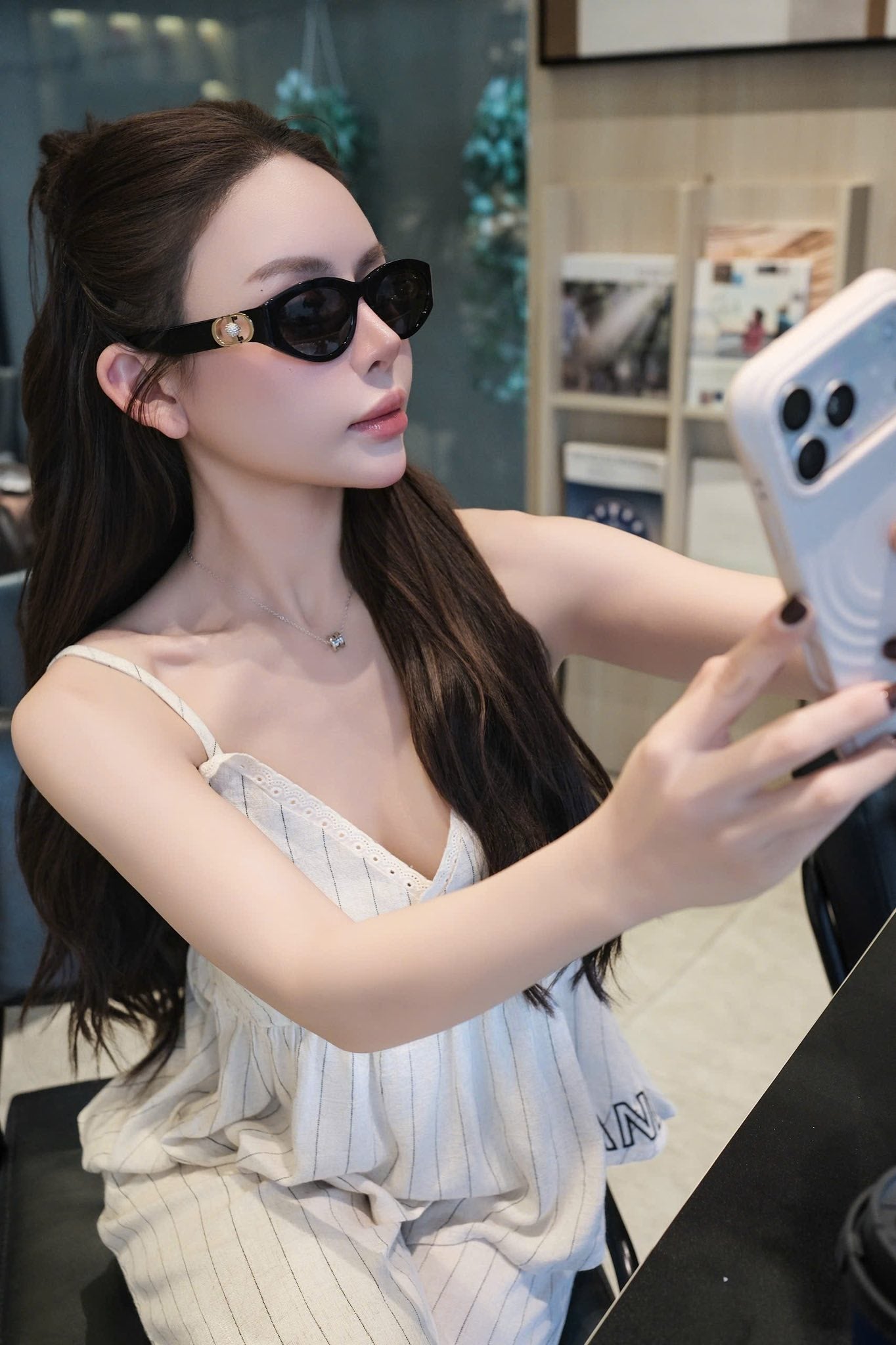 Woman wearing Dior 30Montaigne B7I 10A0 Black Oval Sunglasses and a white dress, taking a selfie.