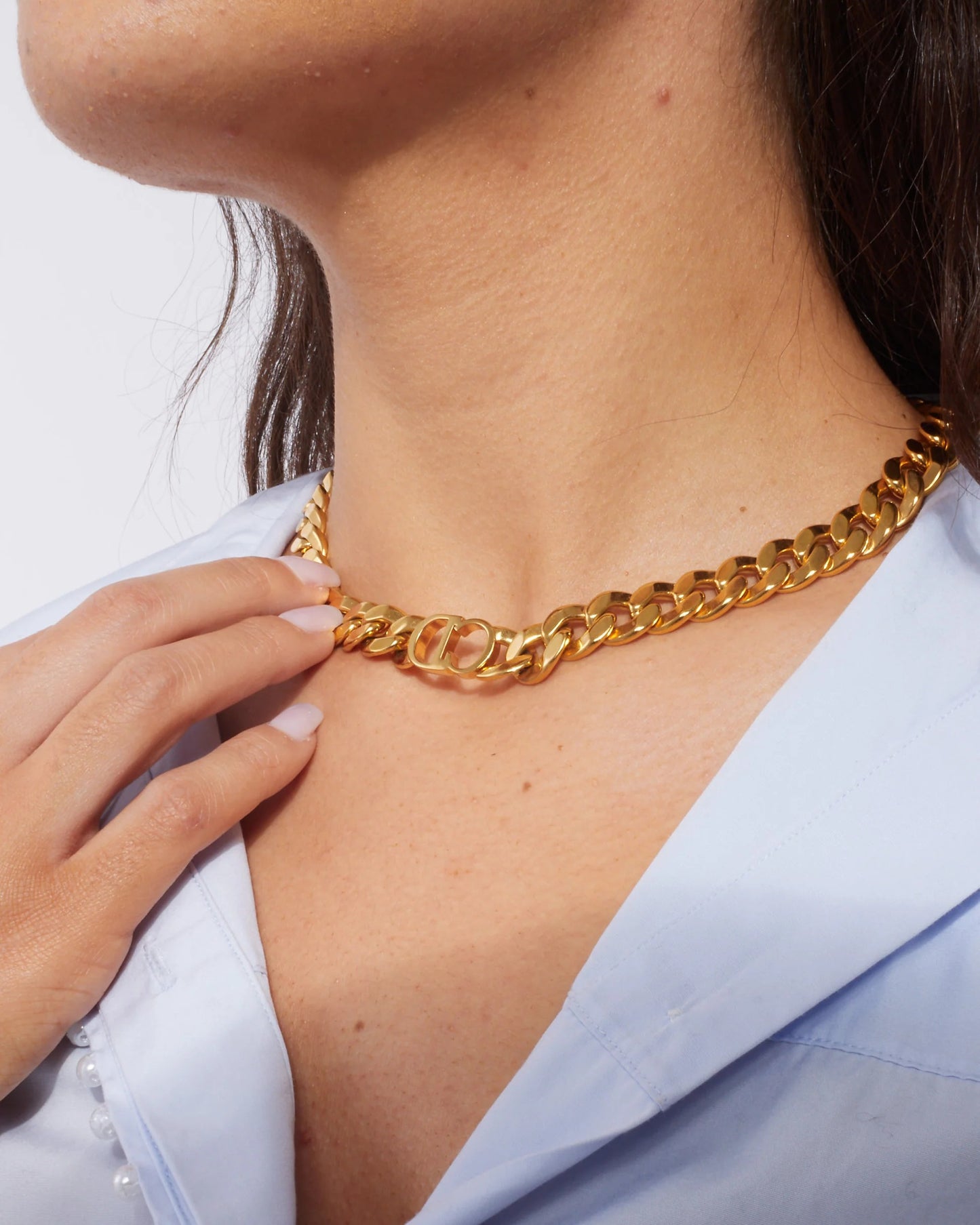 Dior Danseuse Étoile Choker Necklace N0519DSEMT_D300 by a hand on a light blue garment.