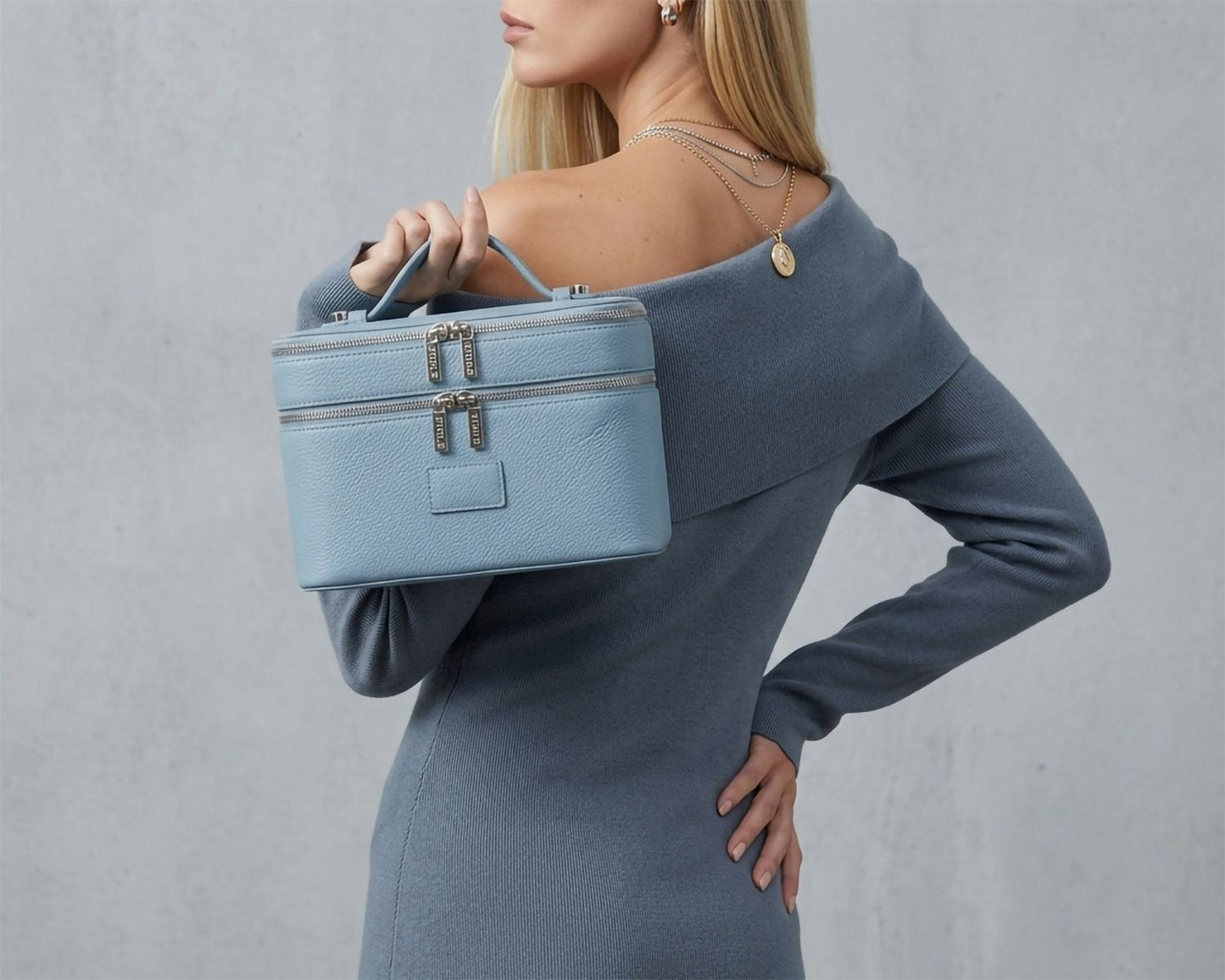Woman holding a Étoile Duo Vanity Case Rodin Blue Limited Edition against a gray background