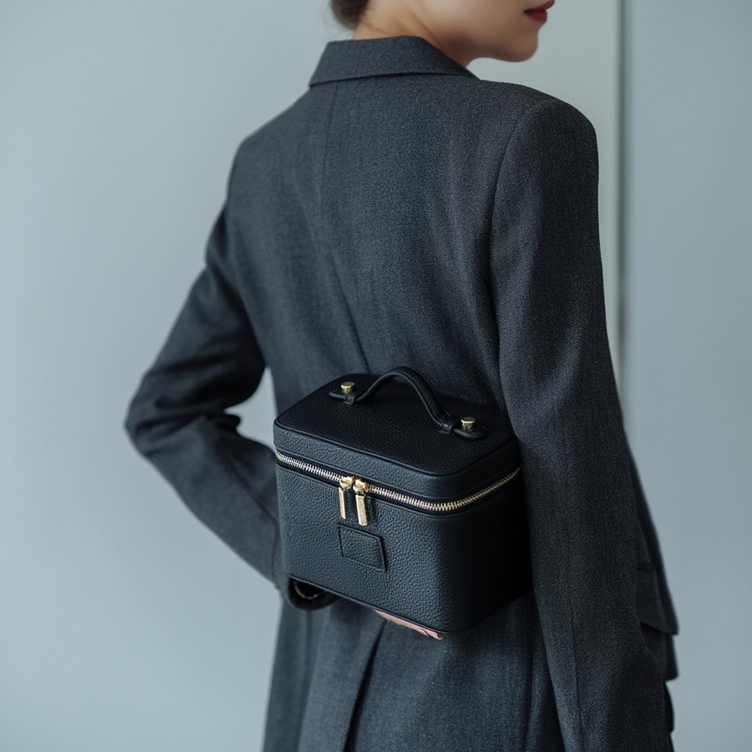 Person holding a Etoile Vanity Case Black with gold zippers on a plain background