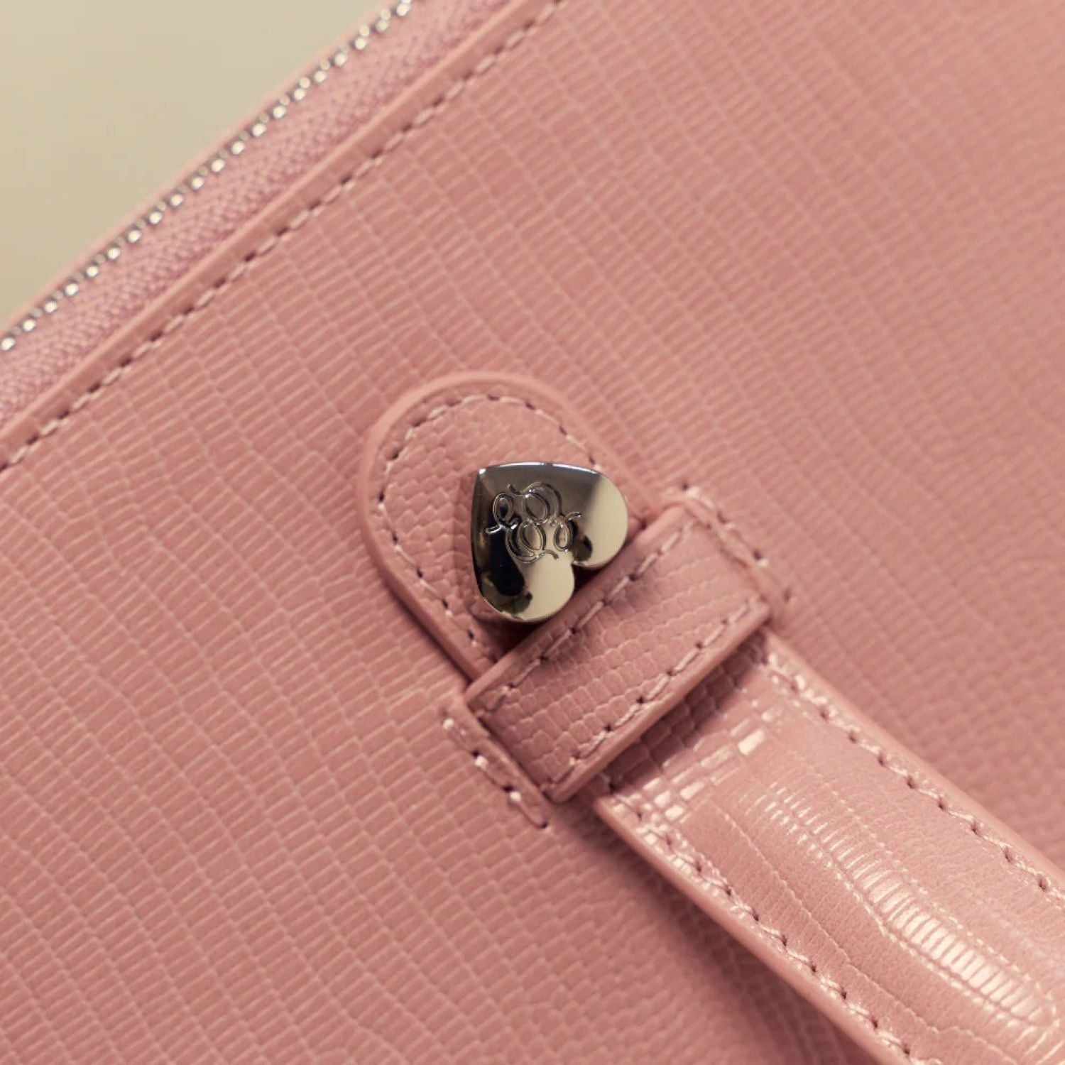 Close-up of a Étoile Vanity Case Crush Limited Edition with a heart-shaped clasp on a light green background