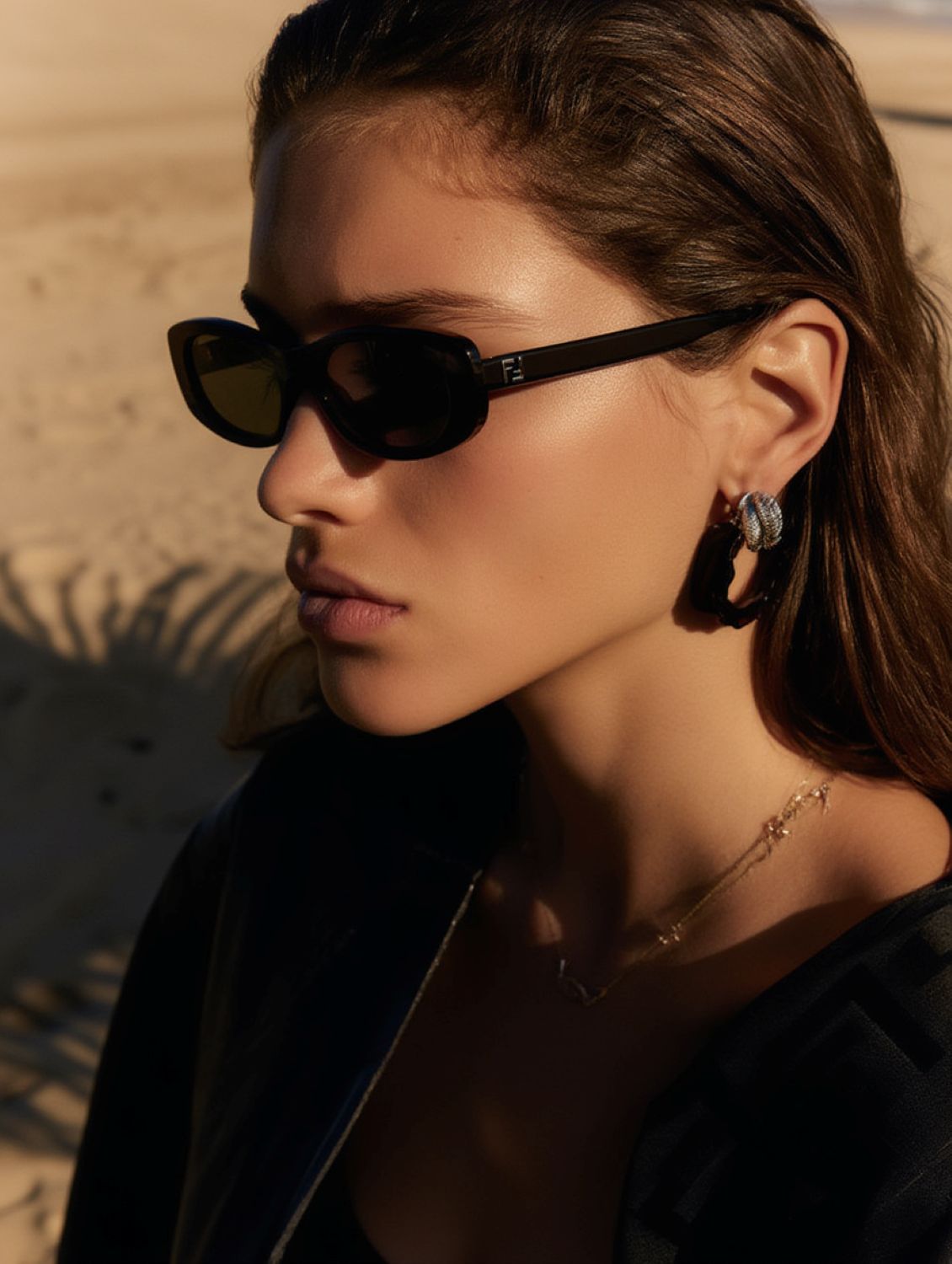 Woman wearing Fendi FE40183I 01A — FF Black Oval Sunglasses with a blurred background