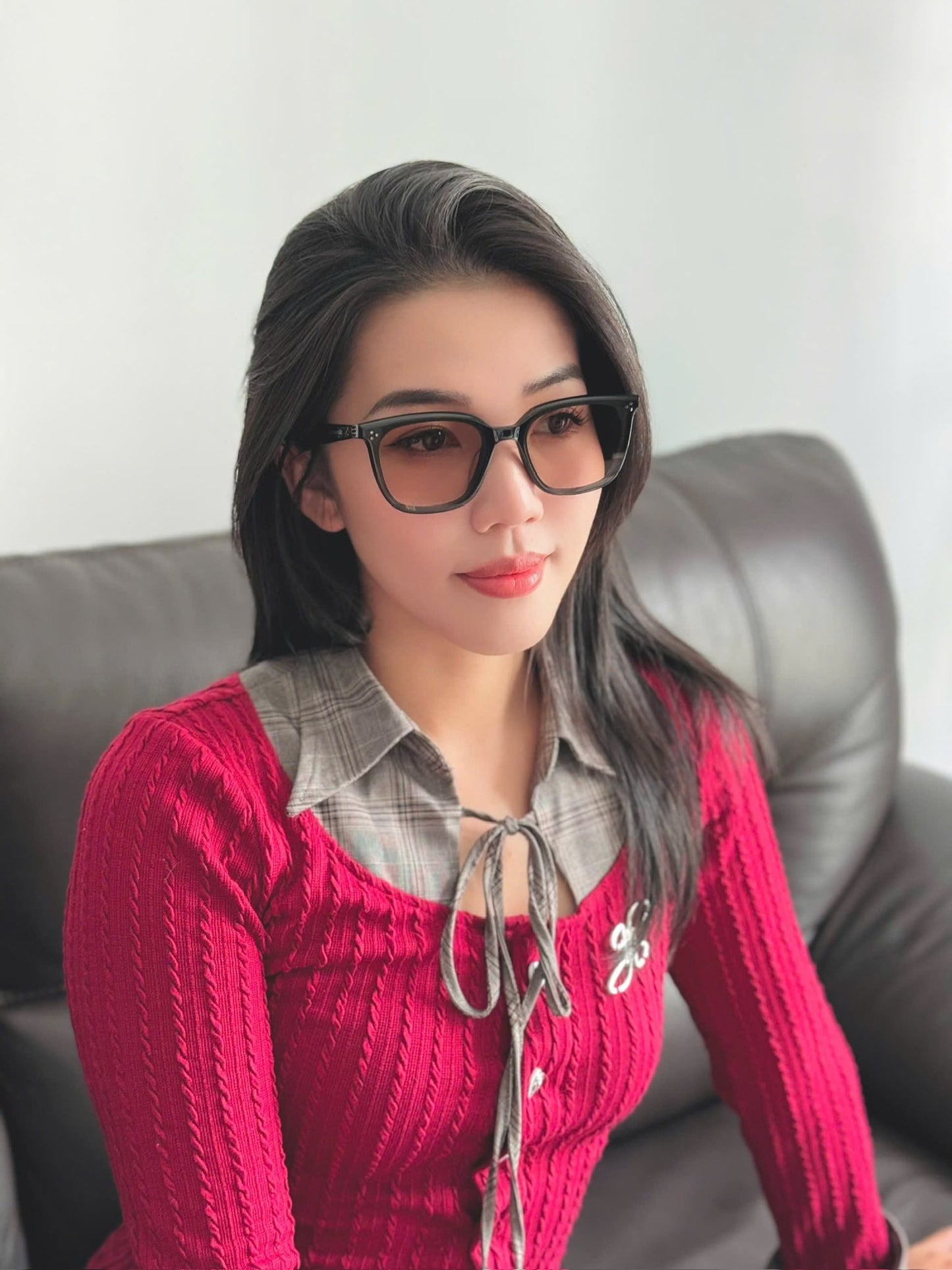 Woman wearing GENTLE MONSTER BY ROW 01(BR) and a red sweater sitting on a couch.