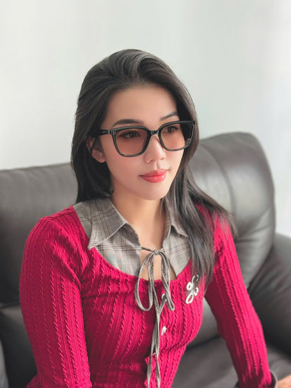 Woman wearing GENTLE MONSTER BY ROW 01(BR) and a red sweater sitting on a couch.