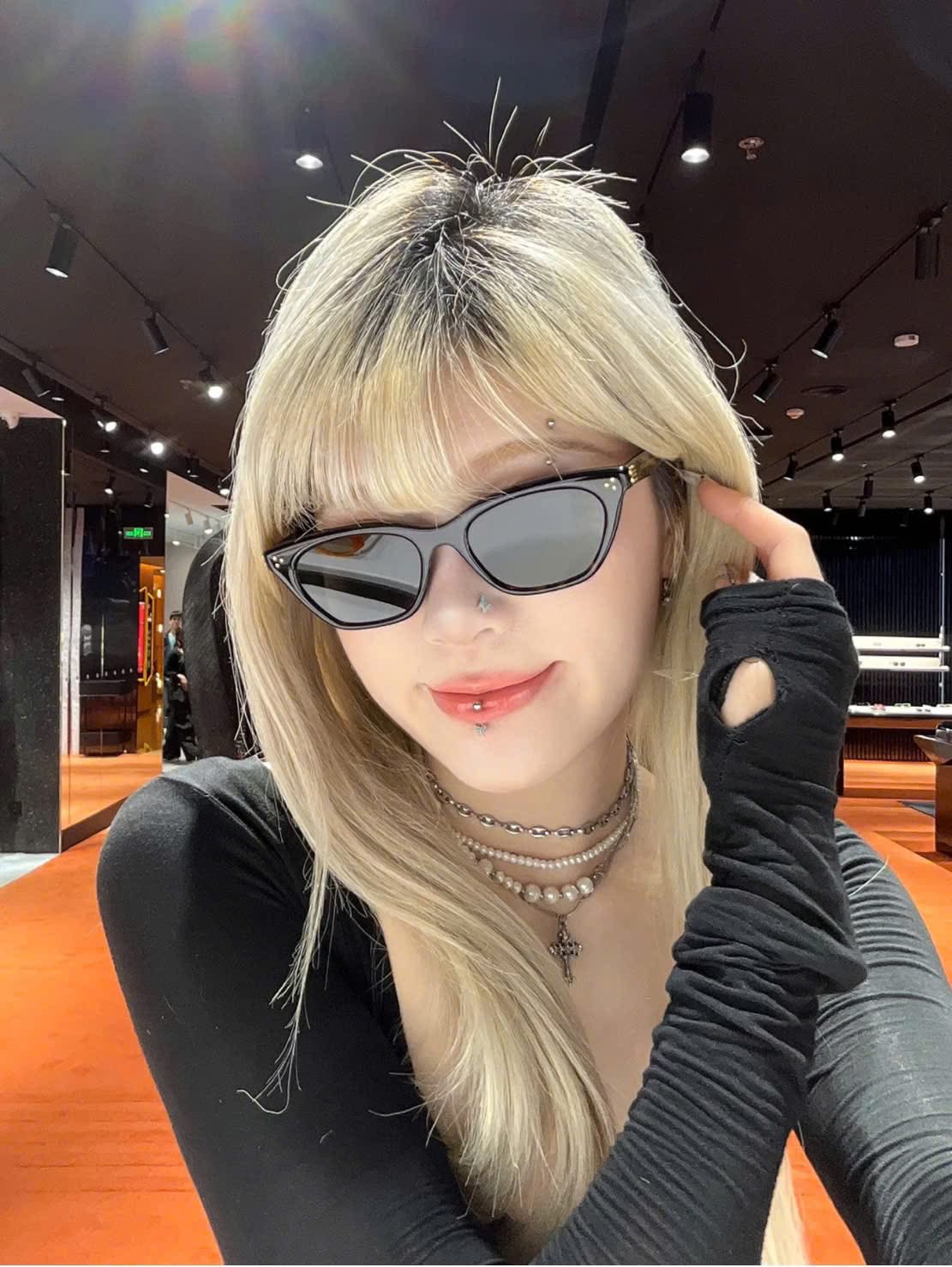 Women wearing Gentle Monster Gisele T1 Cat-Eye Sunglasses and a black outfit in an indoor setting