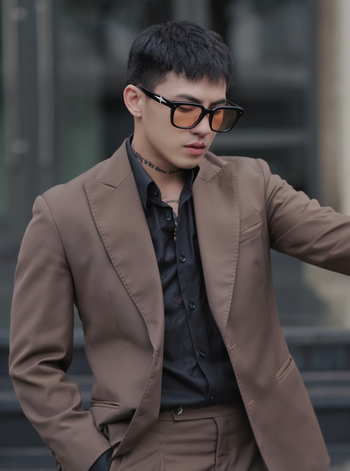 Man wearing a brown blazer and black shirt with Gentle Monster - GM Alto 01(BR), standing outdoors.