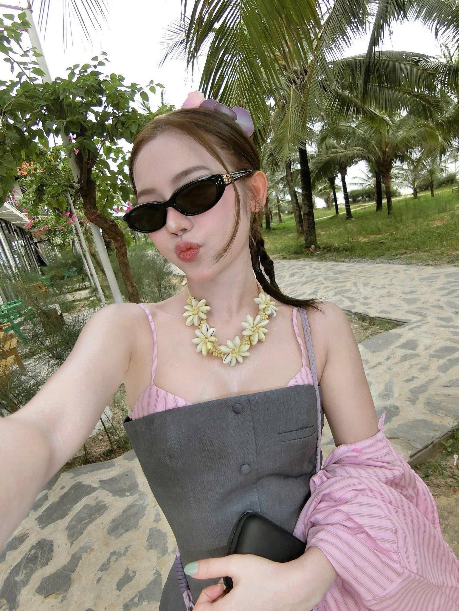 Woman wearing Gentle Monster (GM) Duns 01 and a pink top with a gray apron in a park setting
