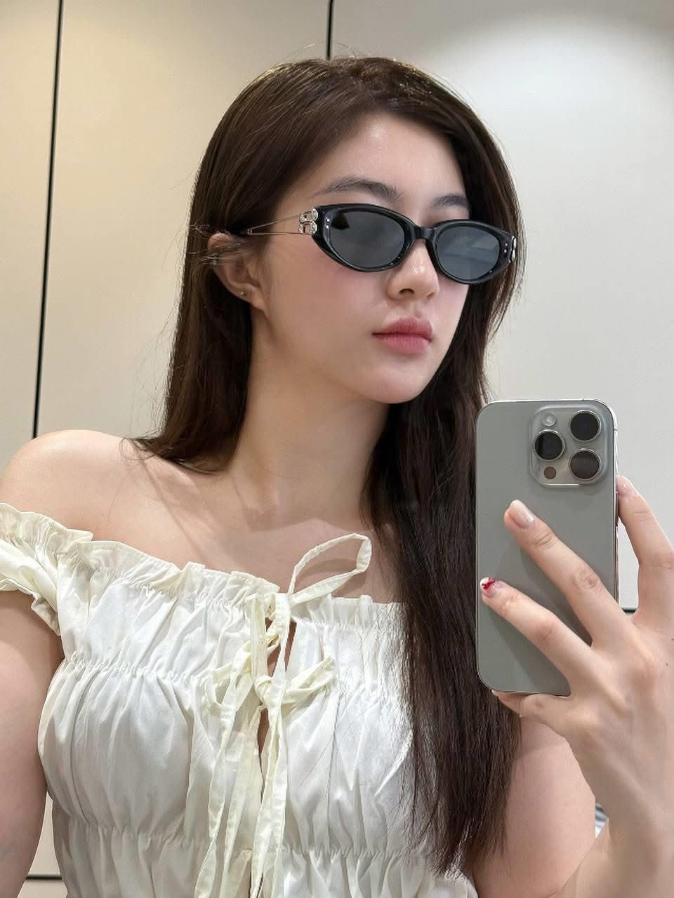 Woman wearing Gentle Monster (GM) Kunst 01 and taking a mirror selfie with a phone.
