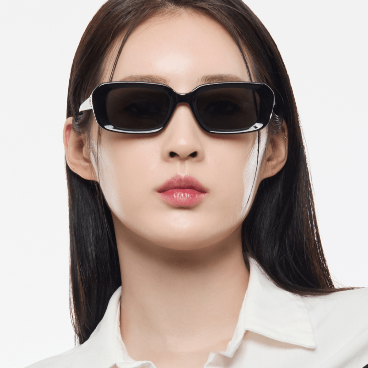 Woman wearing dark sunglasses with a plain background