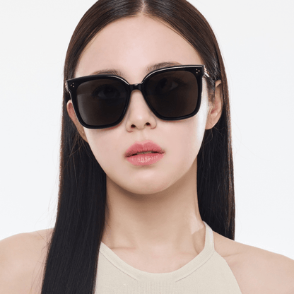Woman wearing black sunglasses with a plain background