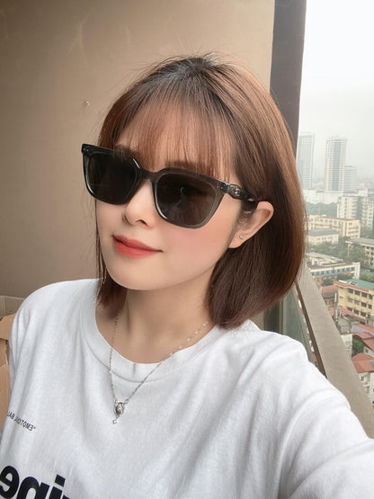 Person wearing Gentle Monster (GM) Nubo G3 with a cityscape in the background