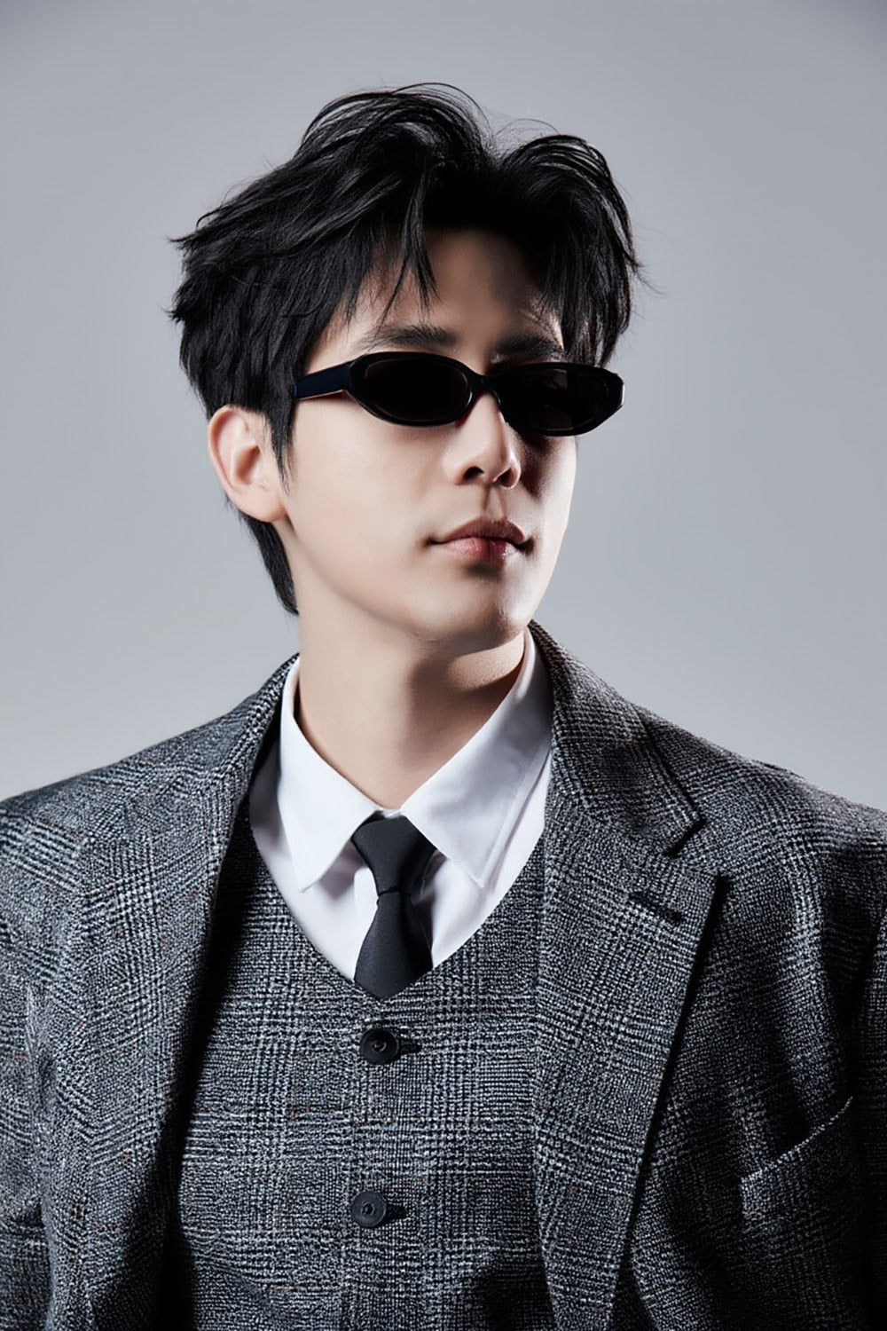 Wang An Yu wearing a gray suit and Gentle Monster Monica 01 Cat-Eye Sunglasses against a gray background