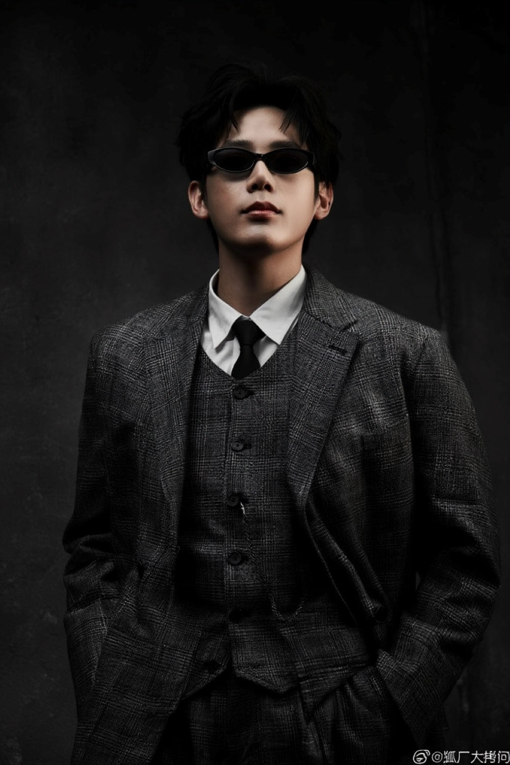 Person wearing a formal suit and Gentle Monster Monica 01 Cat-Eye Sunglasses  against a dark background