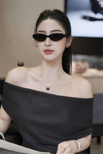 Woman wearing a black off-shoulder top and Gentle Monster Monica 01 Cat-Eye Sunglasses indoors.