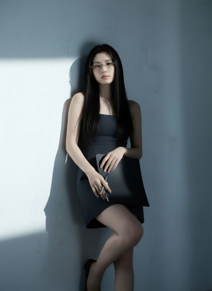 Woman wearing Gentle Monster Musubi 02 in a black dress holding a clutch against a gray wall