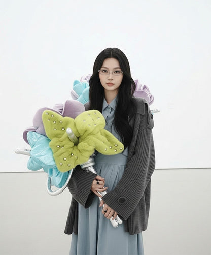 Woman holding colorful butterfly-shaped flowers & wearing Gentle Monster Origami 02 against a white background