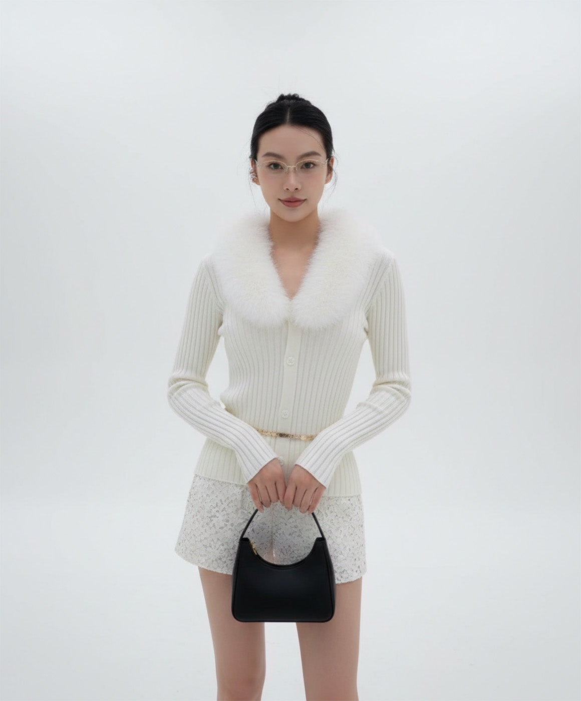 Woman wearing Gentle Monster Origami 031 in a white knit outfit with fur collar and holding a black handbag on a white background