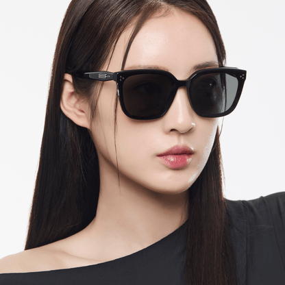 Woman wearing black sunglasses with a plain background