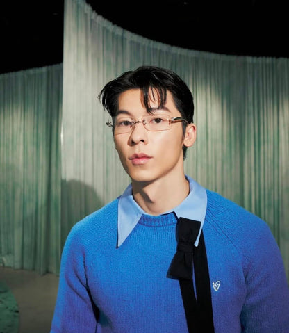 Greg Hsu / Greg Han wearing a Gentle Monster Paranoyd 02(CM) Square Glasses and blue sweater with a black tie against a green curtain background
