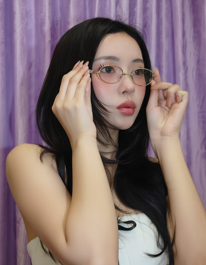 Woman adjusting Gentle Monster Pico 02 Oval Glasses against a purple curtain background