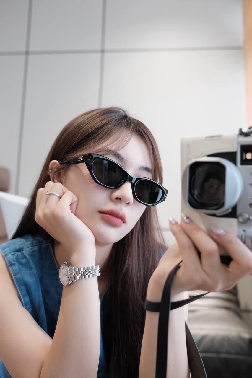 Woman wearing Gentle Monster (GM) Rococo 01 and holding a vintage camera.