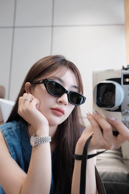 Woman wearing Gentle Monster (GM) Rococo 01 and holding a vintage camera.