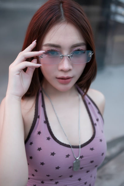 Woman wearing a purple top with star patterns and holding Gentle Monster Tetra 02(BRM) Square Sunglasses.