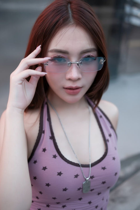 Woman wearing a purple top with star patterns and holding Gentle Monster Tetra 02(BRM) Square Sunglasses.