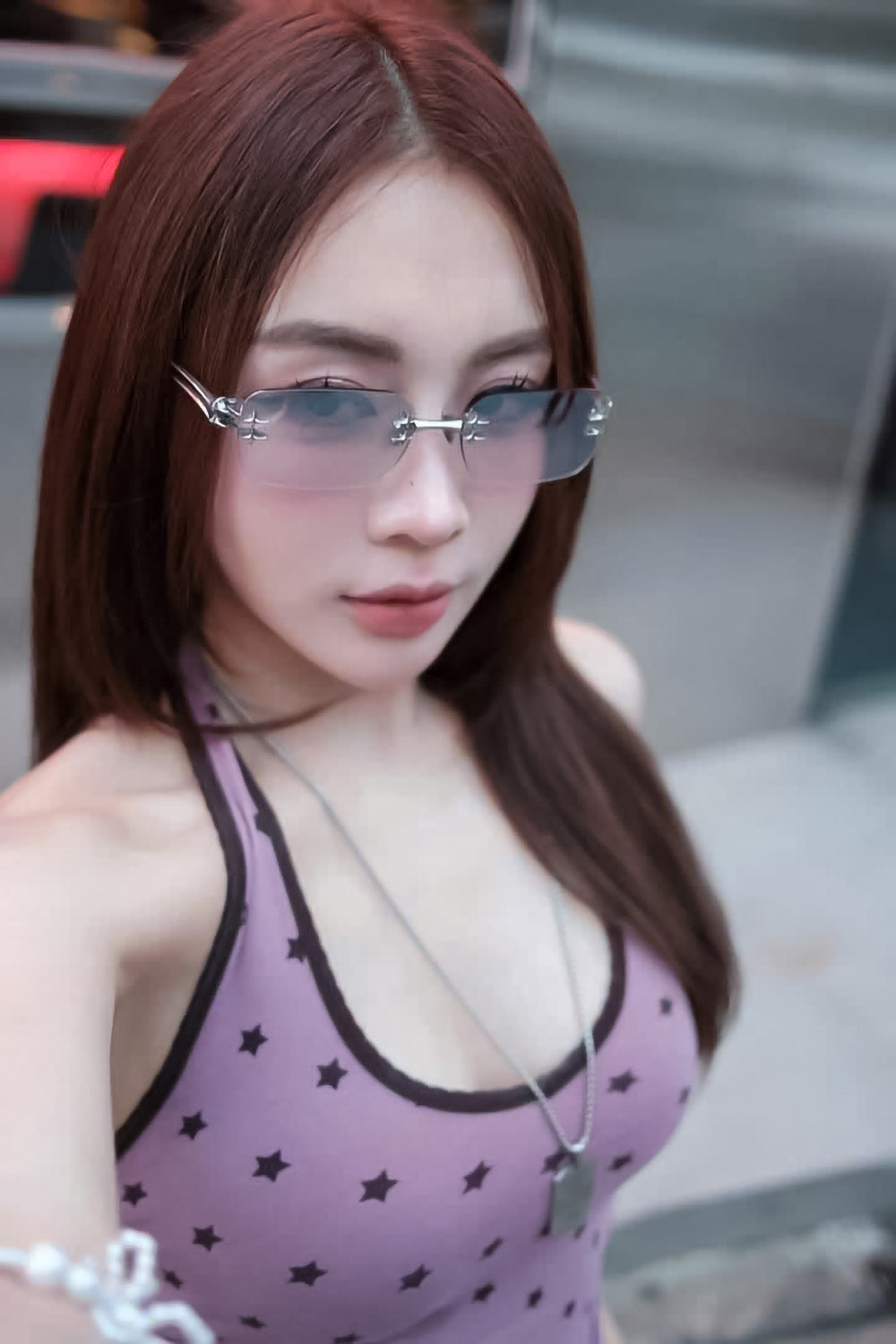 Woman wearing a purple tank top with star patterns and Gentle Monster Tetra 02(BRM) Square Sunglasses in an urban setting.