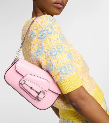 Person wearing a yellow floral-patterned sweater holding a Gucci Asymmetrical Horsebit 1955 Mini Shoulder Bag Light Pink 774209-1DB0N-5823