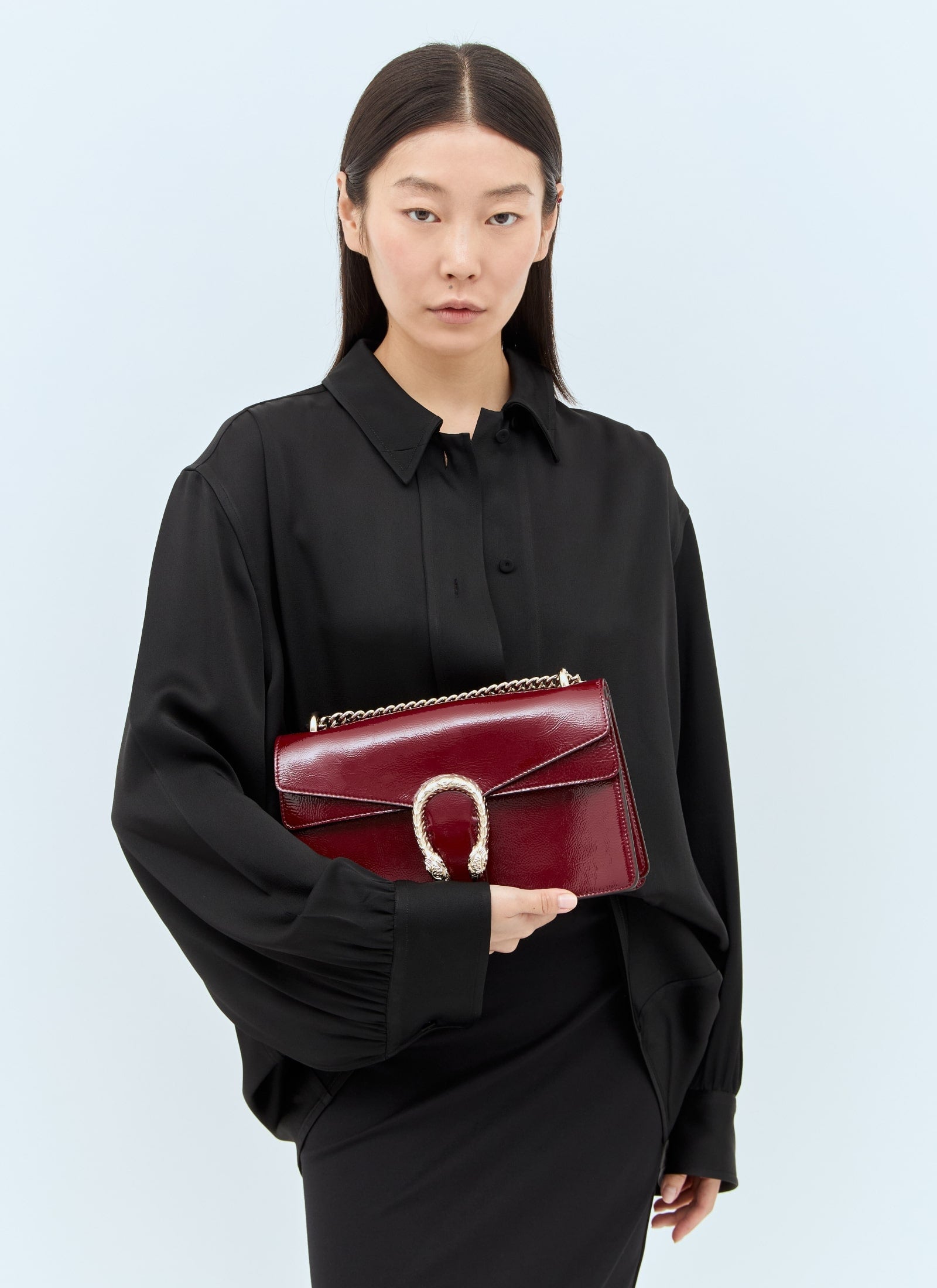 Woman holding a Gucci Dionysus Medium Shoulder Bag Rosso Ancora 795005 0AAA8 6207 against a light blue background