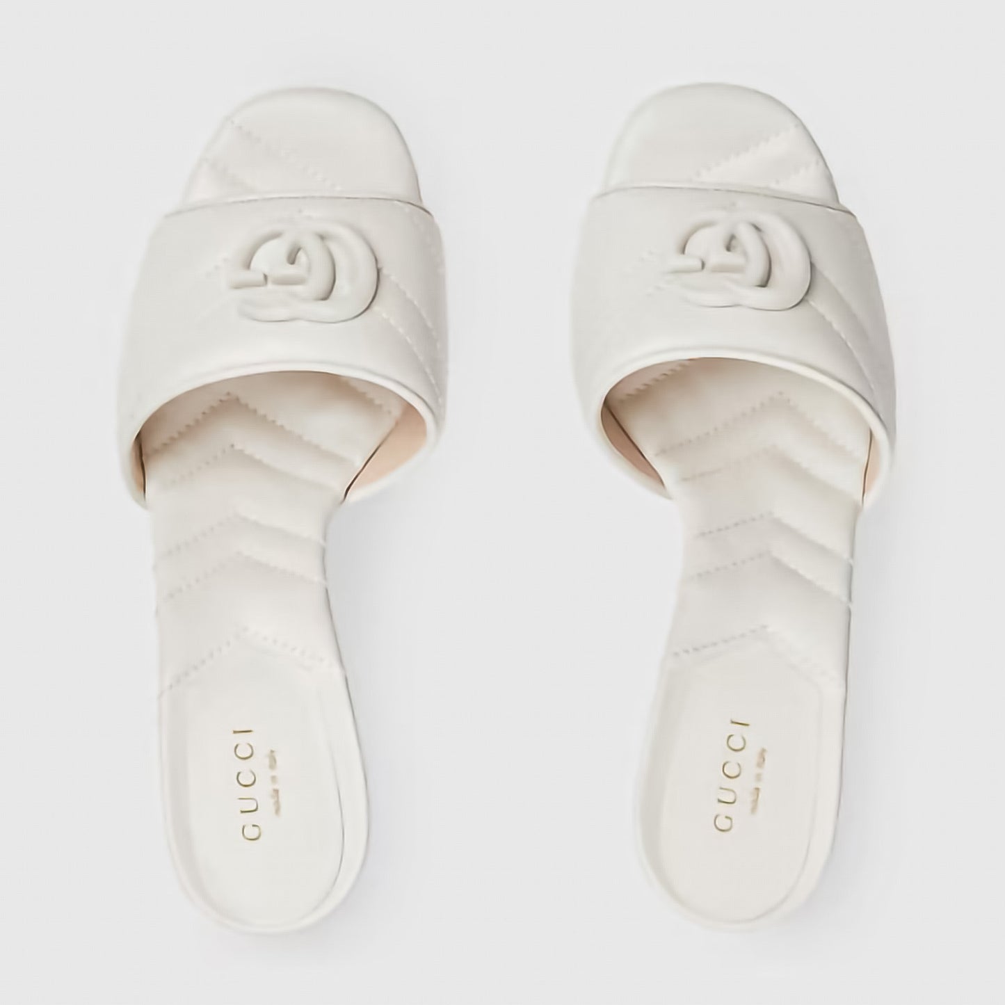 Pair of Gucci slides on a light gray background