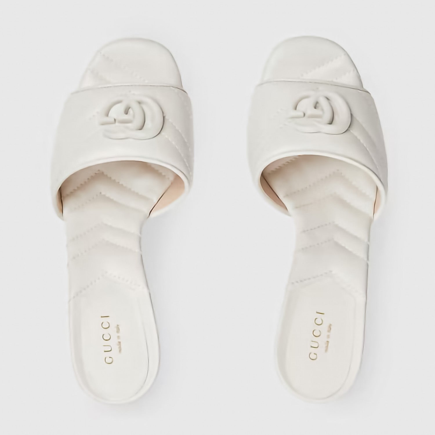 Pair of Gucci slides on a light gray background