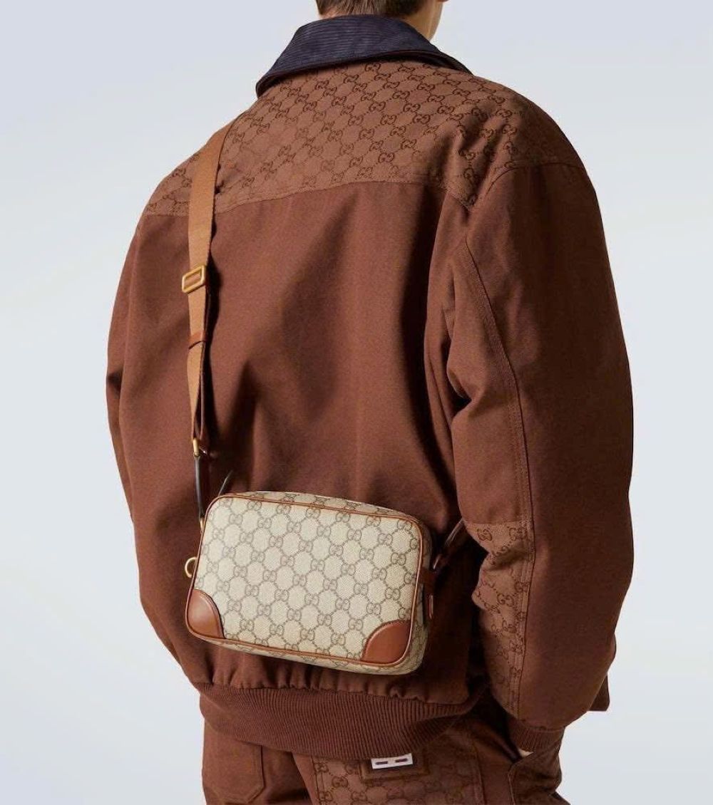 Person wearing a brown jacket with a matching Gucci GG Embossed Super Mini Cognac Beige Shoulder Bag 821216 FAED3 9786 on a light gray background
