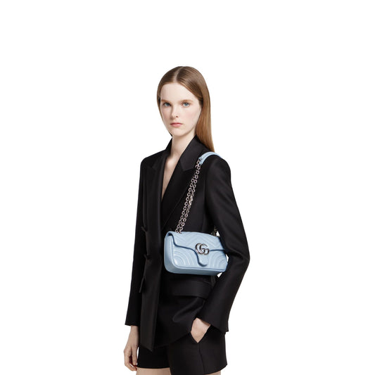 Woman carrying a Gucci GG Marmont Small Shoulder Bag Light Blue Leather 837280 AAFA1 4928 with a brand logo on a white background
