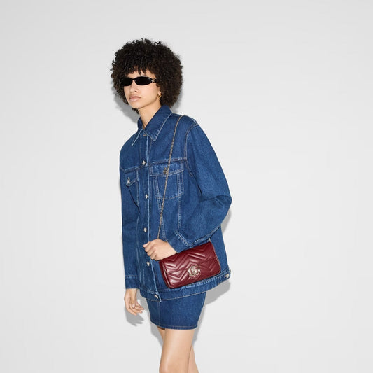 Person wearing a denim jacket and holding a Gucci GG Marmont Small Shoulder Bag Rosso Ancora with Card Case 751526 AADQM 6241 on a white background
