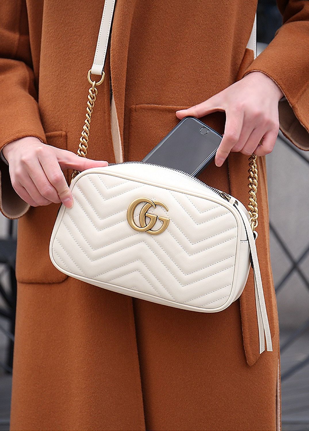women holding Gucci GG White Marmont Small Crossbody Bag 447632 DTD1T 9022 putting the phone inside it