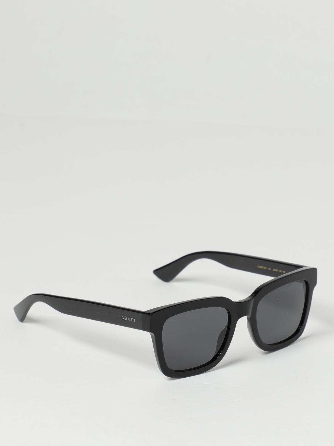 Gucci GG0001SN Black Rectangular Sunglasses with dark gray lenses, shown at an angle on a light gray background.