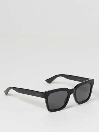 Gucci GG0001SN Black Rectangular Sunglasses with dark gray lenses, shown at an angle on a light gray background.