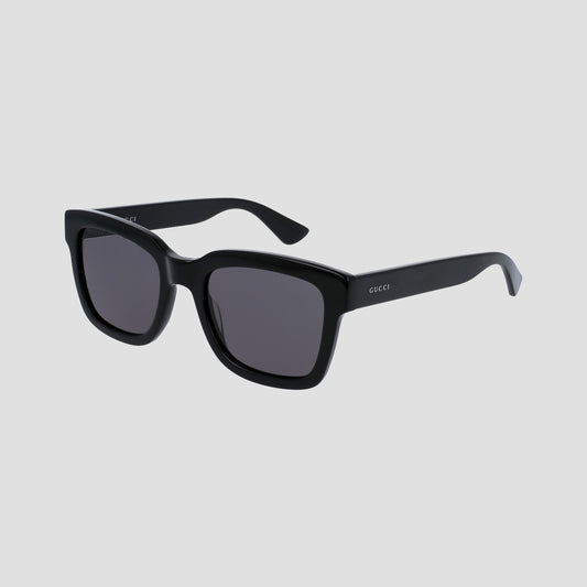 Gucci GG0001SN Black Rectangular Sunglasses with dark gray lenses and a small white GUCCI logo on the temple, shown on a light gray background.