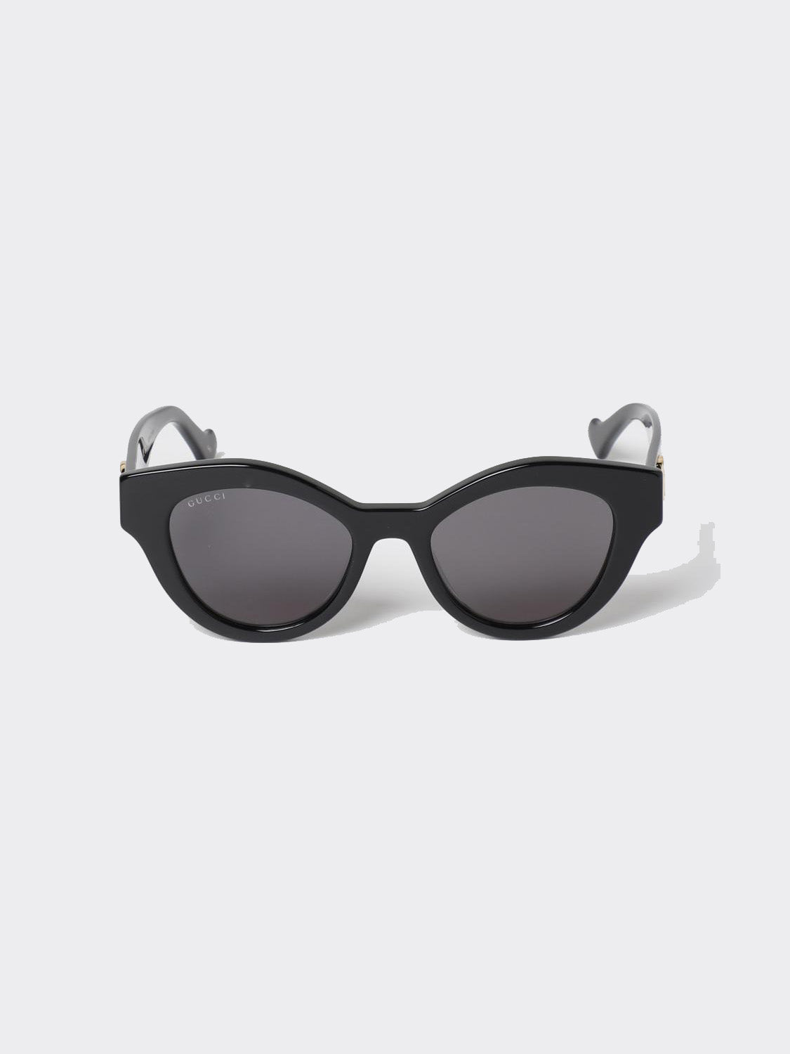 Gucci GG0957S 002 Black Butterfly Rounded Sunglasses with dark lenses and gray temples, photographed on a light gray background.