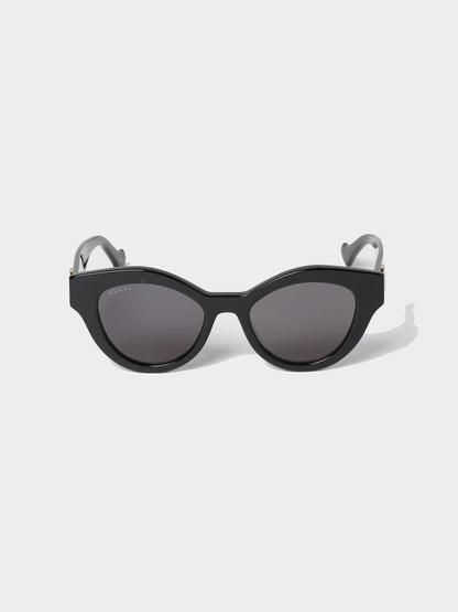 Gucci GG0957S 002 Black Butterfly Rounded Sunglasses with dark lenses and gray temples, photographed on a light gray background.