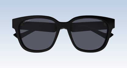 Gucci GG1430SK 001 Black Squared Sunglasses with a thick black frame and dark gray lenses, shown from the front against a light blue gradient background.