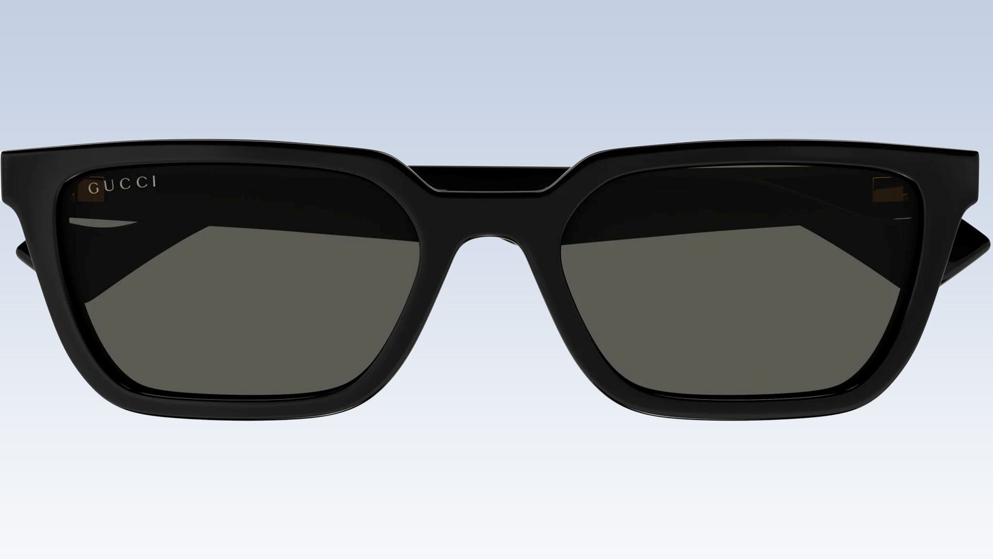 Gucci GG1539S 001 Black Rectangular Sunglasses with a glossy black frame and dark gray lenses, shown against a light blue gradient background.