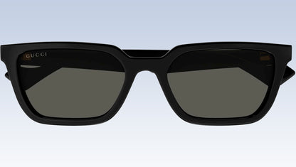 Gucci GG1539S 001 Black Rectangular Sunglasses with a glossy black frame and dark gray lenses, shown against a light blue gradient background.