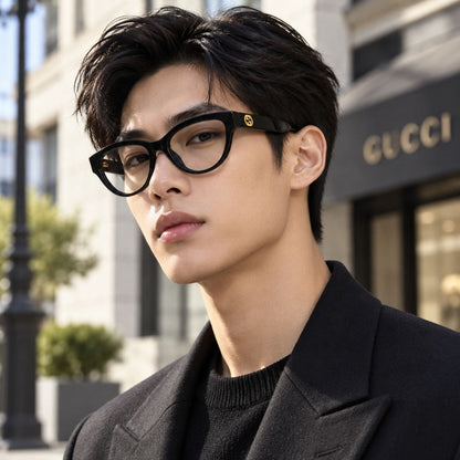 A man wearing Gucci GG1581O Black Cat-Eye Eyeglasses with a small gold logo accent on the temple, photographed outdoors in front of a blurred Gucci storefront.